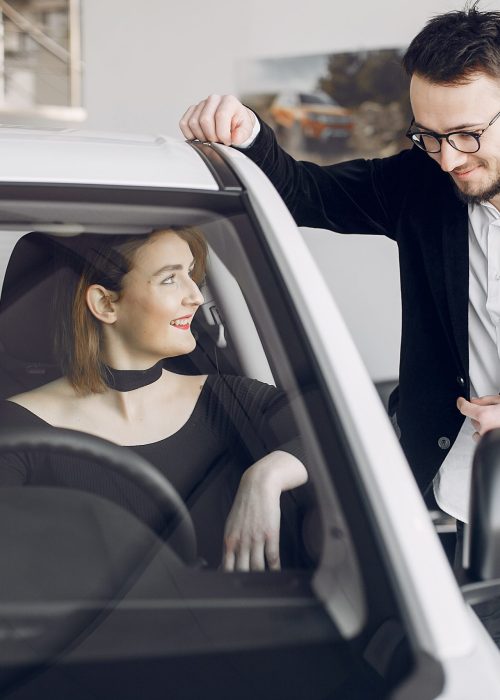 Lady in a car salon. Woman buying the car. Elegant woman in a dress. Assistent with a client